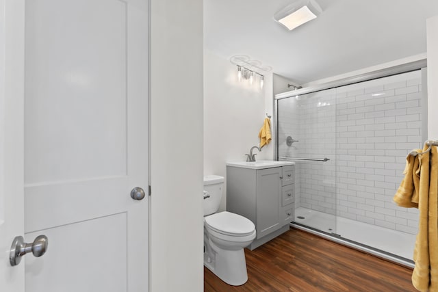 bathroom featuring toilet, hardwood / wood-style flooring, a shower with door, and vanity