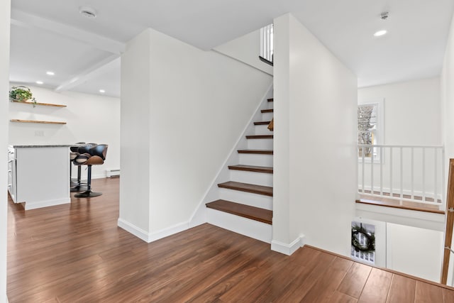 stairs with beam ceiling, a baseboard radiator, and hardwood / wood-style flooring