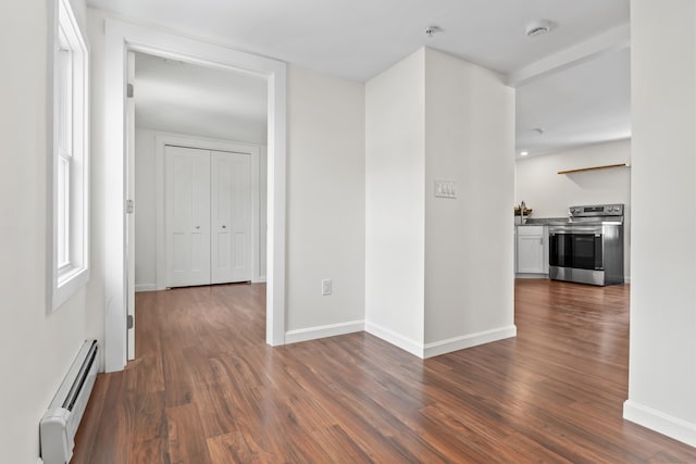 corridor with a baseboard radiator and dark wood-type flooring