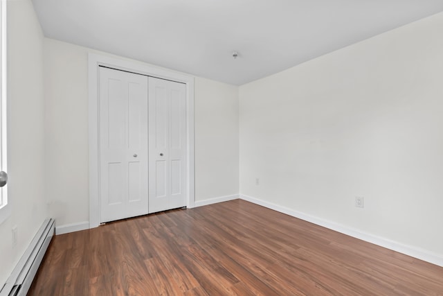 unfurnished bedroom featuring a baseboard radiator, a closet, and dark hardwood / wood-style floors