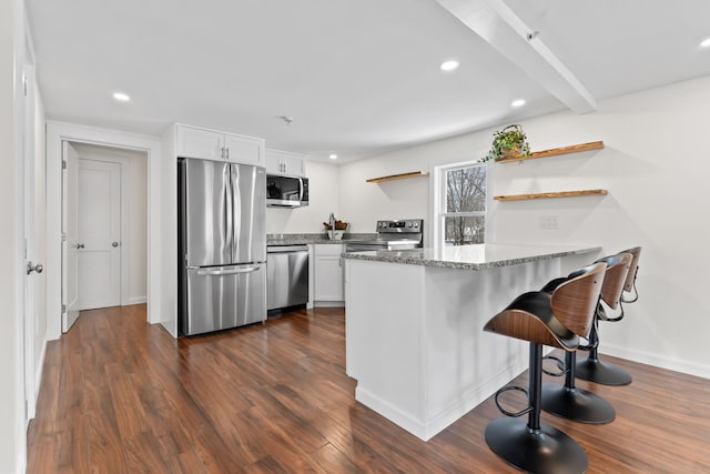 kitchen featuring kitchen peninsula, light stone countertops, dark hardwood / wood-style floors, white cabinets, and appliances with stainless steel finishes