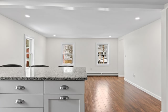 kitchen with a baseboard heating unit, dark wood-type flooring, stone counters, and gray cabinets