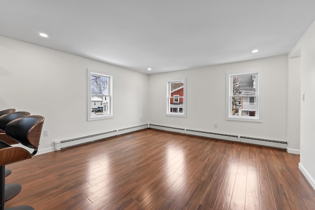 spare room with dark wood-type flooring and a baseboard heating unit