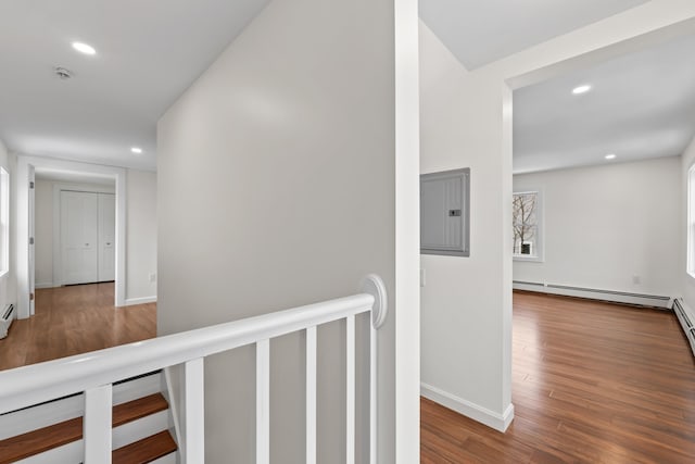 hall featuring electric panel, wood-type flooring, and a baseboard heating unit