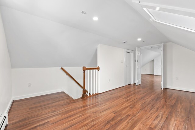 bonus room with dark hardwood / wood-style flooring, a baseboard heating unit, and vaulted ceiling