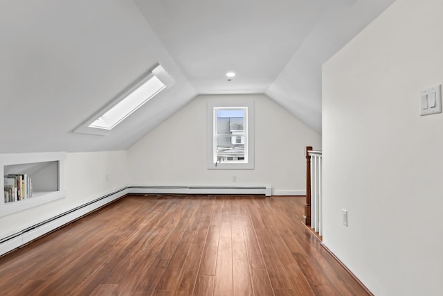 additional living space featuring a baseboard heating unit, vaulted ceiling with skylight, and hardwood / wood-style floors