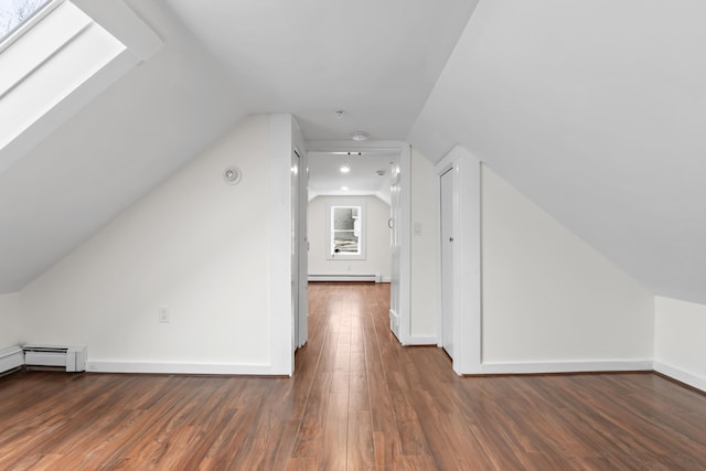 bonus room featuring a baseboard heating unit, lofted ceiling with skylight, and dark hardwood / wood-style flooring