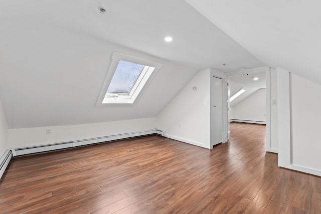 additional living space featuring a baseboard radiator, lofted ceiling with skylight, and dark wood-type flooring