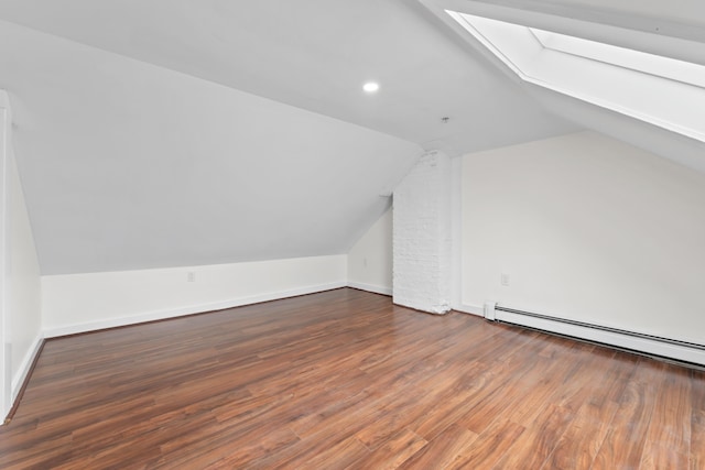 additional living space featuring dark hardwood / wood-style flooring, lofted ceiling with skylight, and baseboard heating