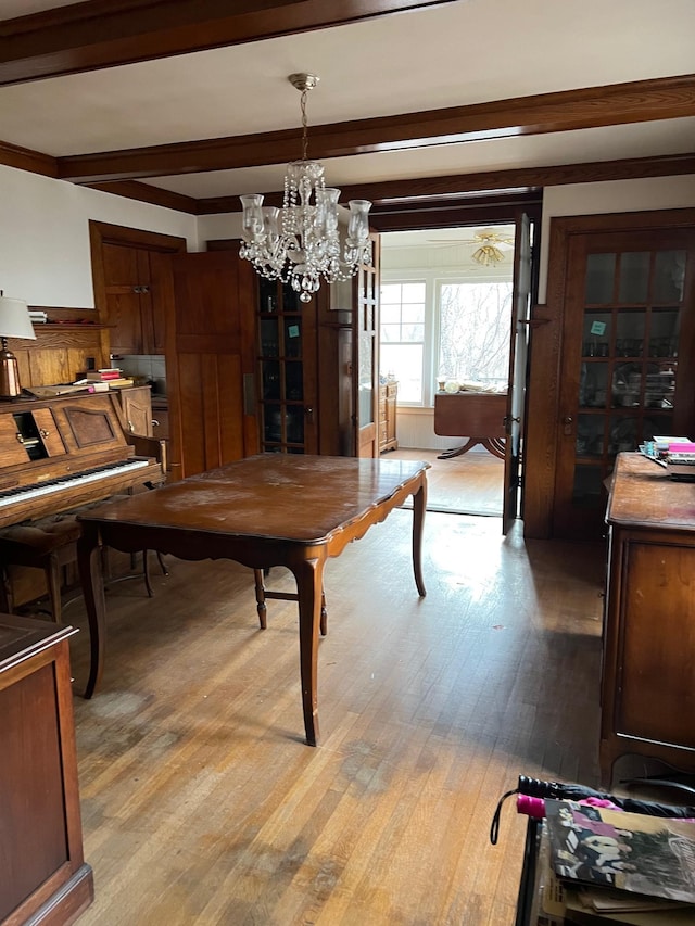 dining room featuring light hardwood / wood-style flooring, beam ceiling, and a chandelier