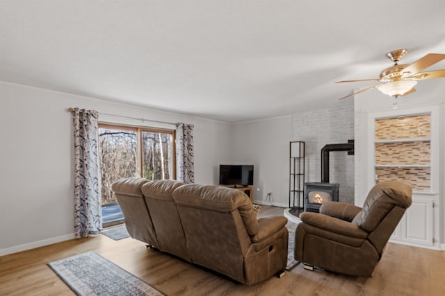 living room with ceiling fan, a wood stove, and light hardwood / wood-style flooring