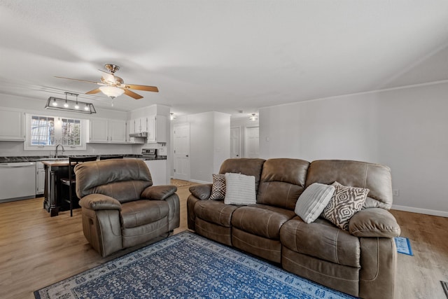 living room featuring ceiling fan, light hardwood / wood-style floors, and sink