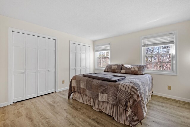 bedroom with light wood-type flooring and multiple closets