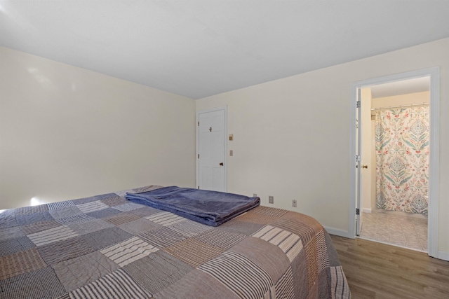 bedroom with ensuite bathroom and hardwood / wood-style floors