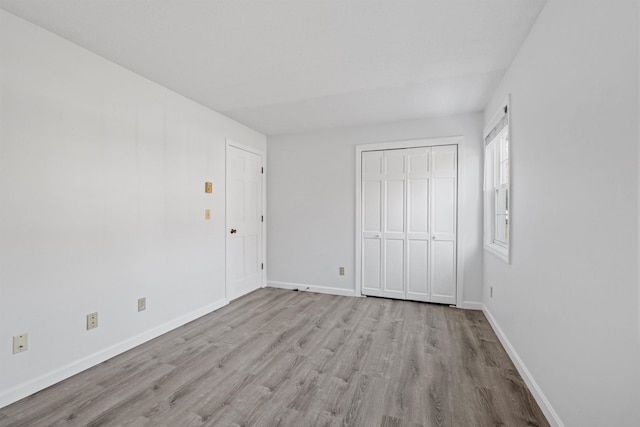 unfurnished bedroom with light wood-type flooring and a closet