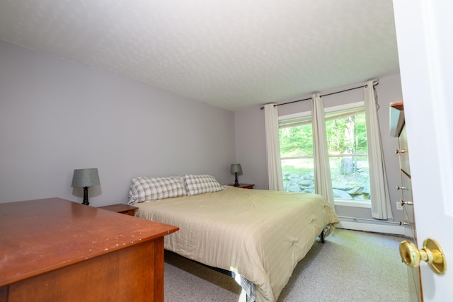 bedroom with a textured ceiling, light carpet, and a baseboard radiator