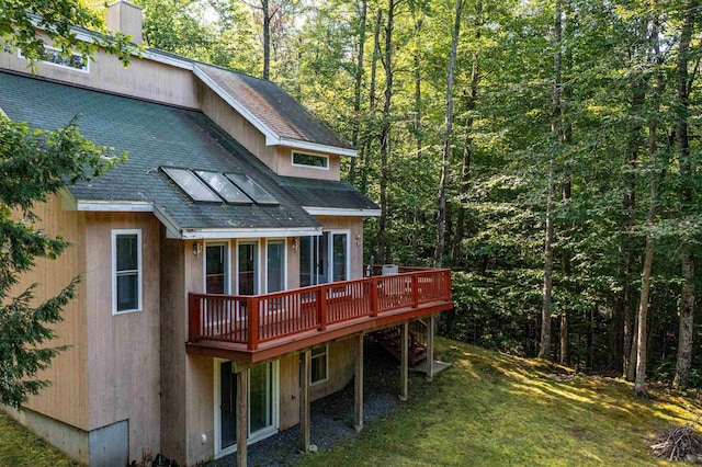 back of property featuring a lawn and a deck