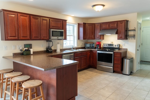 kitchen with sink, a kitchen breakfast bar, kitchen peninsula, and appliances with stainless steel finishes