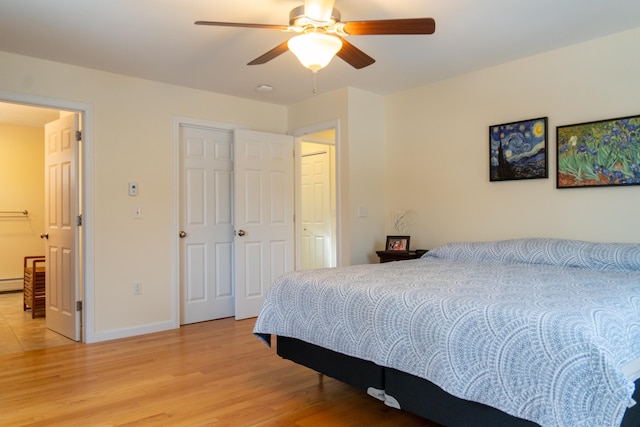 bedroom with ceiling fan, baseboard heating, and hardwood / wood-style floors