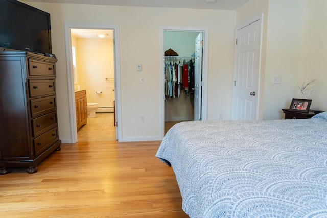 bedroom featuring baseboard heating, a closet, a walk in closet, light hardwood / wood-style flooring, and ensuite bathroom