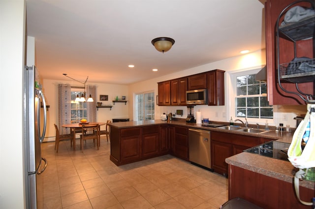 kitchen with a chandelier, appliances with stainless steel finishes, kitchen peninsula, sink, and decorative light fixtures