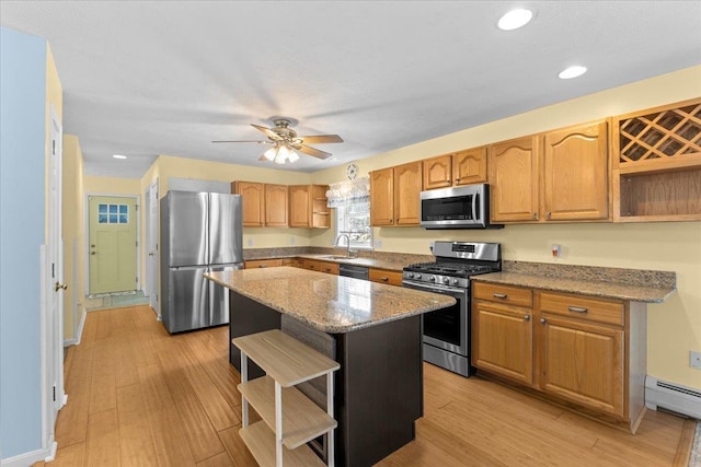 kitchen featuring light stone countertops, a center island, stainless steel appliances, a baseboard heating unit, and ceiling fan