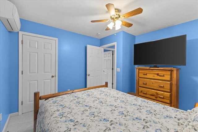 carpeted bedroom featuring an AC wall unit, ceiling fan, and a textured ceiling