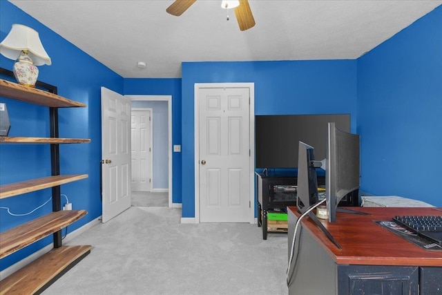 carpeted home office with a textured ceiling and ceiling fan