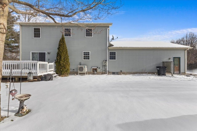 snow covered house featuring ac unit and a wooden deck