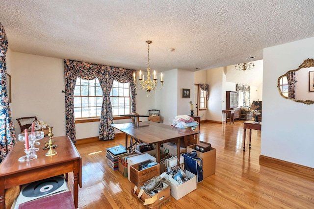 dining room featuring a textured ceiling, light hardwood / wood-style flooring, and a chandelier