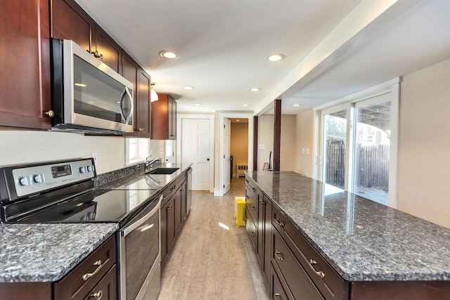 kitchen featuring sink, dark stone countertops, stainless steel appliances, and light hardwood / wood-style flooring