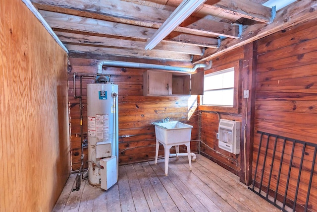 interior space featuring wood walls, light hardwood / wood-style floors, beamed ceiling, heating unit, and water heater