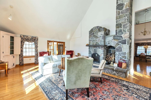 living room with high vaulted ceiling, hardwood / wood-style floors, a chandelier, and a fireplace