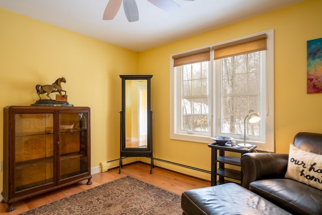 living area featuring a wealth of natural light, ceiling fan, a baseboard radiator, and wood-type flooring