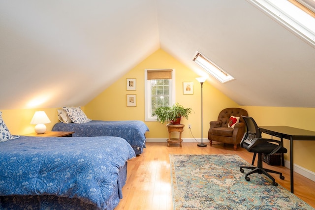 bedroom with hardwood / wood-style flooring and vaulted ceiling with skylight