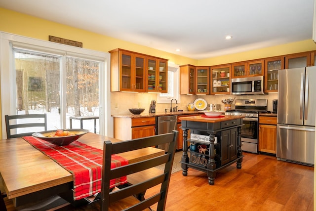 kitchen with appliances with stainless steel finishes, wood-type flooring, backsplash, and a wealth of natural light