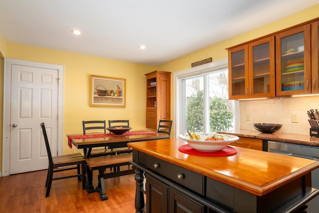 kitchen with light stone counters, dishwasher, light hardwood / wood-style floors, backsplash, and dark brown cabinets