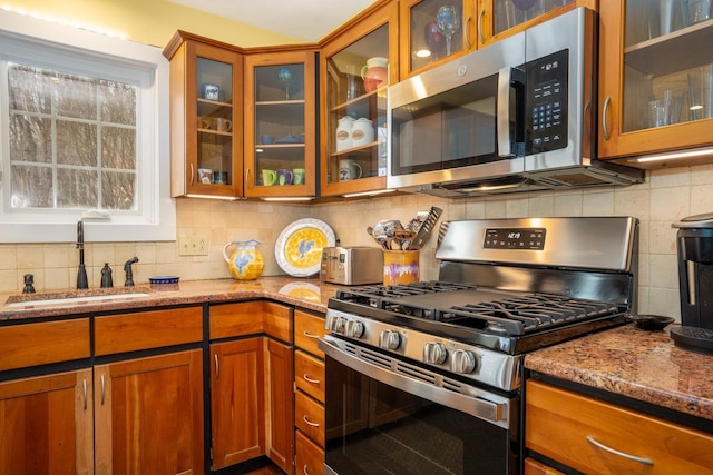 kitchen featuring stainless steel appliances, sink, tasteful backsplash, and dark stone counters