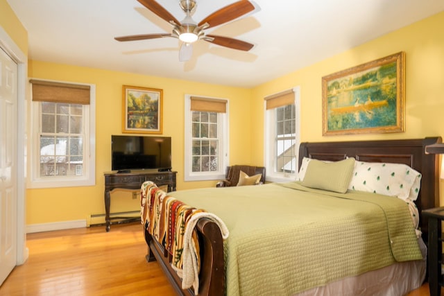 bedroom with baseboard heating, ceiling fan, and light wood-type flooring