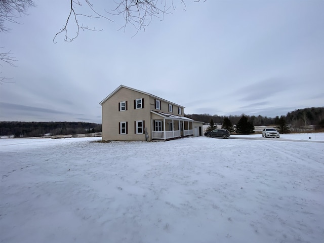 snow covered back of property featuring covered porch