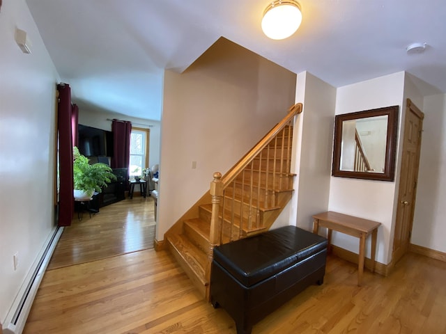 stairs featuring baseboard heating and hardwood / wood-style flooring