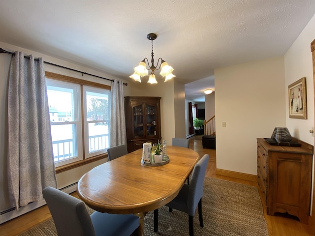 dining room with a baseboard heating unit, a chandelier, and hardwood / wood-style floors