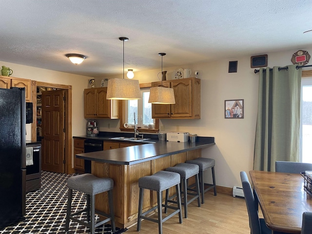 kitchen with sink, decorative light fixtures, kitchen peninsula, a breakfast bar area, and black appliances