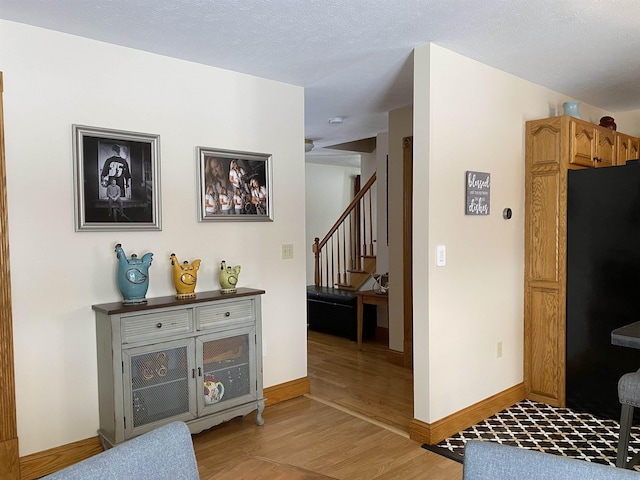 corridor with a textured ceiling and light hardwood / wood-style floors