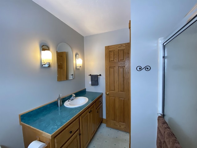 bathroom featuring a shower with door and vanity