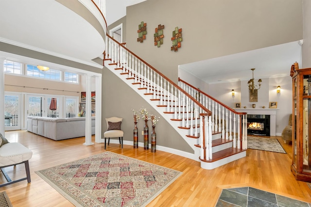 staircase featuring wood-type flooring, a tiled fireplace, and decorative columns