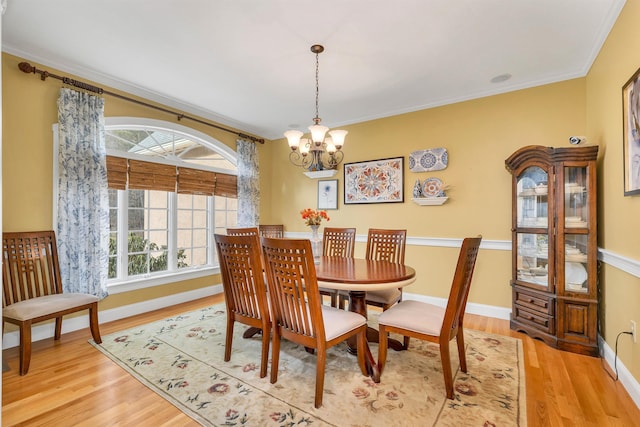 dining room featuring crown molding, light hardwood / wood-style floors, and a notable chandelier