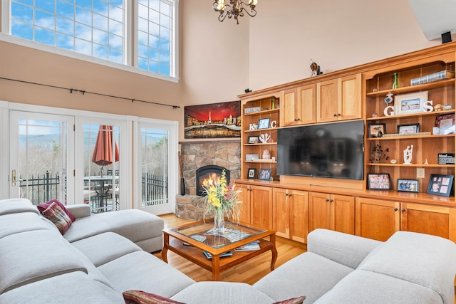 living room with plenty of natural light, light hardwood / wood-style flooring, a towering ceiling, and a fireplace