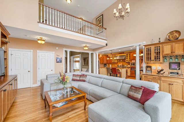 living room featuring a high ceiling, light hardwood / wood-style flooring, and ornate columns