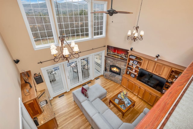 living room with light wood-type flooring, a fireplace, a healthy amount of sunlight, and a towering ceiling